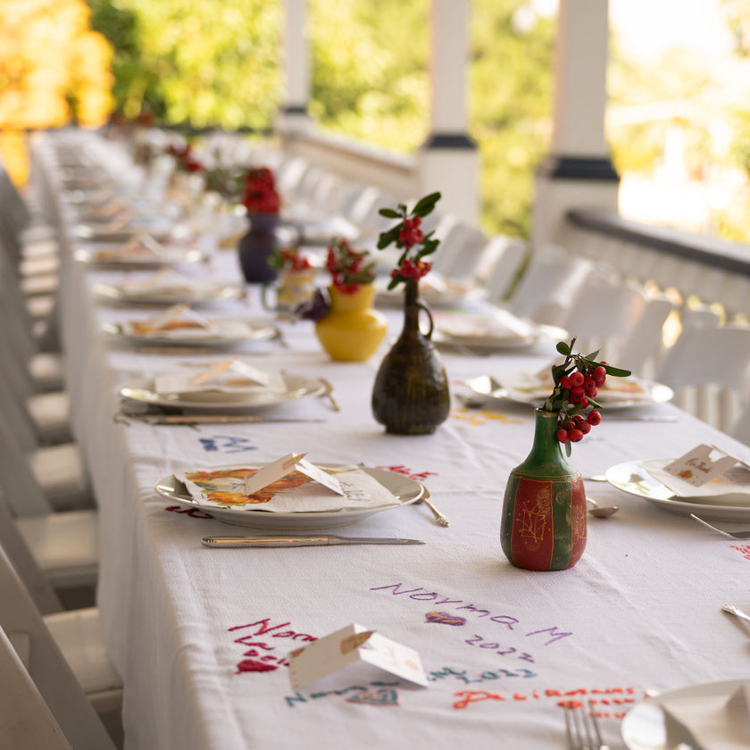 Family Threads tablecloth displayed on a long outdoor holiday table, filled with handwritten signatures.